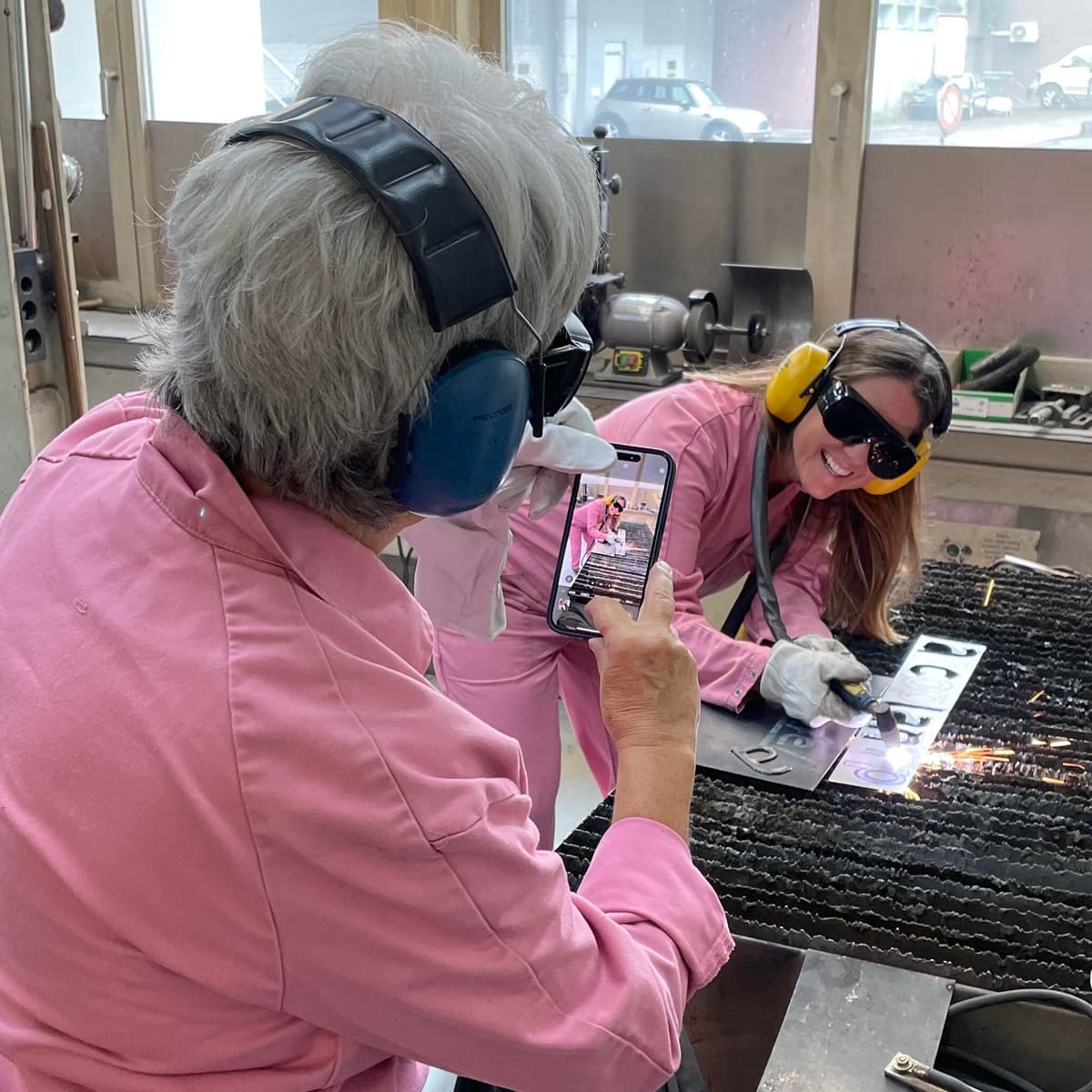 Teilnehmerinnen dokumentieren die Arbeit mit dem Plasmaschneider, im Teamevent bei raumformer in Zuchwil, mit dem Smartphone.